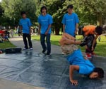 A photo of several boys in matching T-shirts dancing on a paved surface.