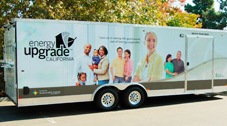 A photo of a long trailer/truck with the Energy Upgrade logo on the side and images of people.