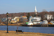Photo of a variety of buildings in an urban area, with a river flowing in the foreground.