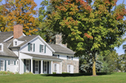 Photo of a residential-looking structure on a grassy stretch, surrounded by healthy trees.