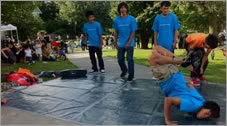 A photo of several boys in matching T-shirts dancing on a paved surface.