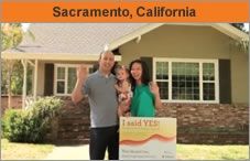 Photo of a family facing the camera, standing in front of a house, the husband with a toddler in his arms. They're in front of a small sign that says 'I said YES!' The headline over the photo reads 'Sacramento, California.'