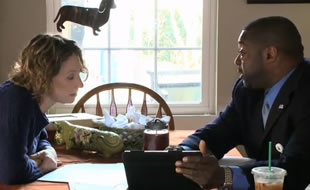 Photo of a man and a woman sitting and talking at a dining room table in a home.