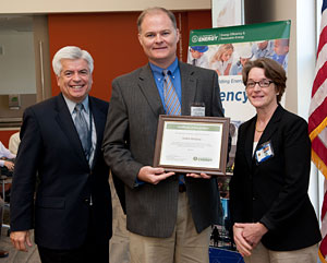 Dr. Kathleen Hogan, DOE Deputy Assistant Secretary for Energy Efficiency (right), presented a framed letter of recognition to a Daikin McQuay representative (center), in recognition that their Rebel™ rooftop unit air-conditioning system met the RTU Challenge.