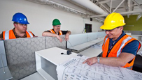 Photo of three construction workers consulting architectural plans.