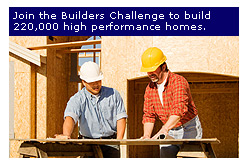 Photo of two men in hard hats standing in front of the wood frame of a house