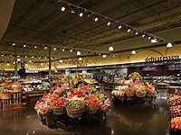 Photo of a grocery store produce department, illuminated by LED track accent lights on the ceiling.