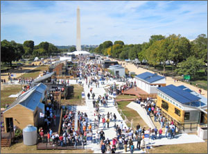 Photo of competition houses at Solar Decathlon 2009, with people visiting the houses and the National Monument rising in the background.
