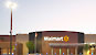 Photo of the front of the Walmart Supercenter at dusk with outside lighting on.