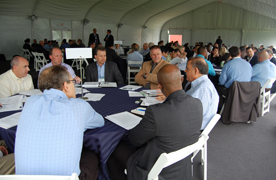 Photo of several small groups of people seated at round tables, engaged in discussion.