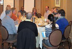 photo of a meeting, with people seated around a table.