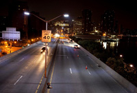 Photo of a road at night with a street light in the foreground.