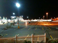 Photo of a shopping plaza showing an LED parking lot light to the left and an HPS light to the right.