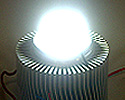 Photo of a bright white globe sitting on top of a column composed of many horizontal metal blades.