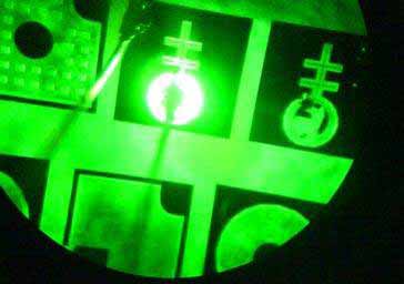 Photo of a microscope image of a mini deep green LED. Image shows part of a circle with intersecting green bands, green and black shapes, and a smaller glowing circle at the center.