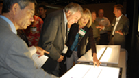 Photo of a group of people looking at a large light fixture on a table.