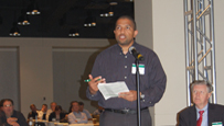 Photo of a man standing behind a microphone.