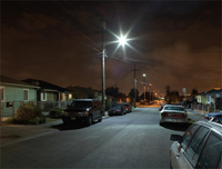 Photo of a residential street at night with a bright streetlight in the center.