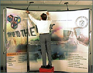 Photo of a man attaching graphic sheets to an exhibit display frame.