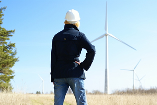 A woman standing in front of a wind-power generator