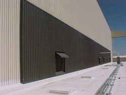 Photo of the wall of a building with a large portion covered with dark colored solar PV material.