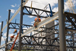 Photo of initial building structure with two workers on large metallic beams.