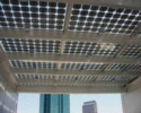 Photo of the underside of a ceiling PV shade structure. Sunlight is visible through the transparent spaces between the PV panels.