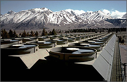 Photo of geothermal cooling towers with fans running. Mountains are in the background.