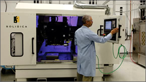 Technician in lab coat attending to the machine that uses ultrasonic energy (sound) instead of heat and pressure to weld materials at a molecular level