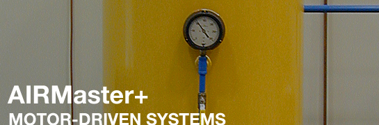 This photo shows the wall of an industrial building with a pressure gauge mounted on the wall. Underneath the gauge in the lower left-hand corner are the words "AIRMaster+" and underneath this title are the words "Motor-Driven Systems."