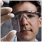 Photo of a man in laboratory goggles holding a small cell.