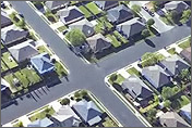 Illustration of a crossroads in suburbia. The road is lined on either side by small houses, surrounded by yards. Illustration links to the Building Technologies Program, Builders Challenge Home page.