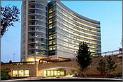 Photo of a large office-style building, taken at dusk. Its sides are covered with windows, many of which are lit. Photo links to the Federal Energy Management Program, Super Energy Savings Performance Contracts.