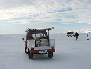 Photo of the back of a small electric truck with an NREL bumper sticker on it parked on snow in Antarctica.