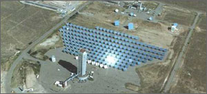 Photo that shows an aerial view of the Test Facility. A central tower looms over a field of ten rows of ground-mounted mirrors that track the sun and focus the sunlight onto the top of the tower.
