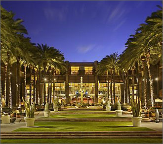 Photo of a grassy elegant walkway lined with potted plants and palm trees approaching the Hyatt Hotel in Scottsdale, Arizona.