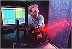 Photo of a researcher using a large-scale laser scanner (LSLS) that uses a laser to scan PV modules and produces an output that can be used to analyze the modules.