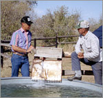 Photo of two ranchers standing in front of a water tank that is solar powered.