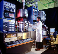 Photo of NREL researcher inspecting a growth chamber of a physical vapor deposition systems.
