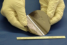 Photo of a gloved researcher holding a thin-film solar cell that was fabricated by MicroLink.