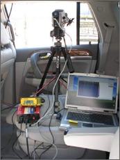 Photo of the inside of a van that holds both a tripod-mounted field infrared camera pointing out the window and a global positioning system unit to measure receiver temperatures of a parabolic trough system outside.
