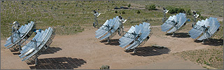 Photo of three rows of dish/engine solar systems, each containing two systems. The dishes are all pointing in the same direction, and each consists of a series of rectangular mirrors assembled into a dish structure.