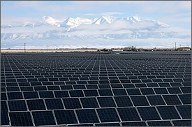 Photo of multiple rows of one-axis tracking photovoltaic panels at the photovoltaic power plant near Alamosa, Colorado. The Rocky Mountains are pictured in the background. Numerous rows of PV arrays are pictured in the foreground.  