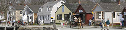 Photo showing the numerous buildings that make up the museum village. Visitors stroll along the road that runs through the village. 