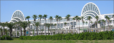 Photo of the Orange County Convention Center in Florida with palm trees and grass visible in the  foreground.