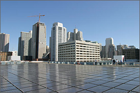 Photo of the solar array installed on the roof of the Moscone Center with city buildings of various sizes visible in the background.