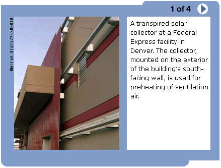 Photo of a transpired solar collector. There are red metal tubes running vertically along the side of a warehouse-sized building that preheat the ventilation air.  (Caption: A transpired solar collector at a Federal Express facility in Denver. The collector, mounted on the exterior of the building's south-facing wall, is used for preheating of ventilation air.)