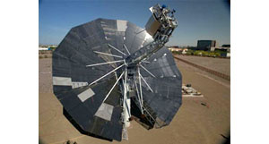 Photo of a large metallic, circular dish that is mounted to the ground with a horizontal bar extending from the center.