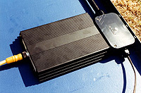 Photo of a black box connected to the back of a solar panel.