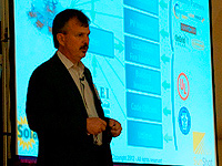 Photo of a man giving a presentation in front of a projector screen.
